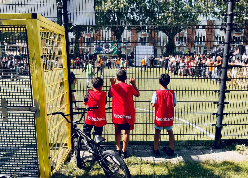 Jongeren kijken naar een straatvoetbalwedstrijd 